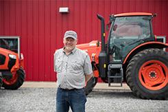 Man st和ing in front of farm equipment